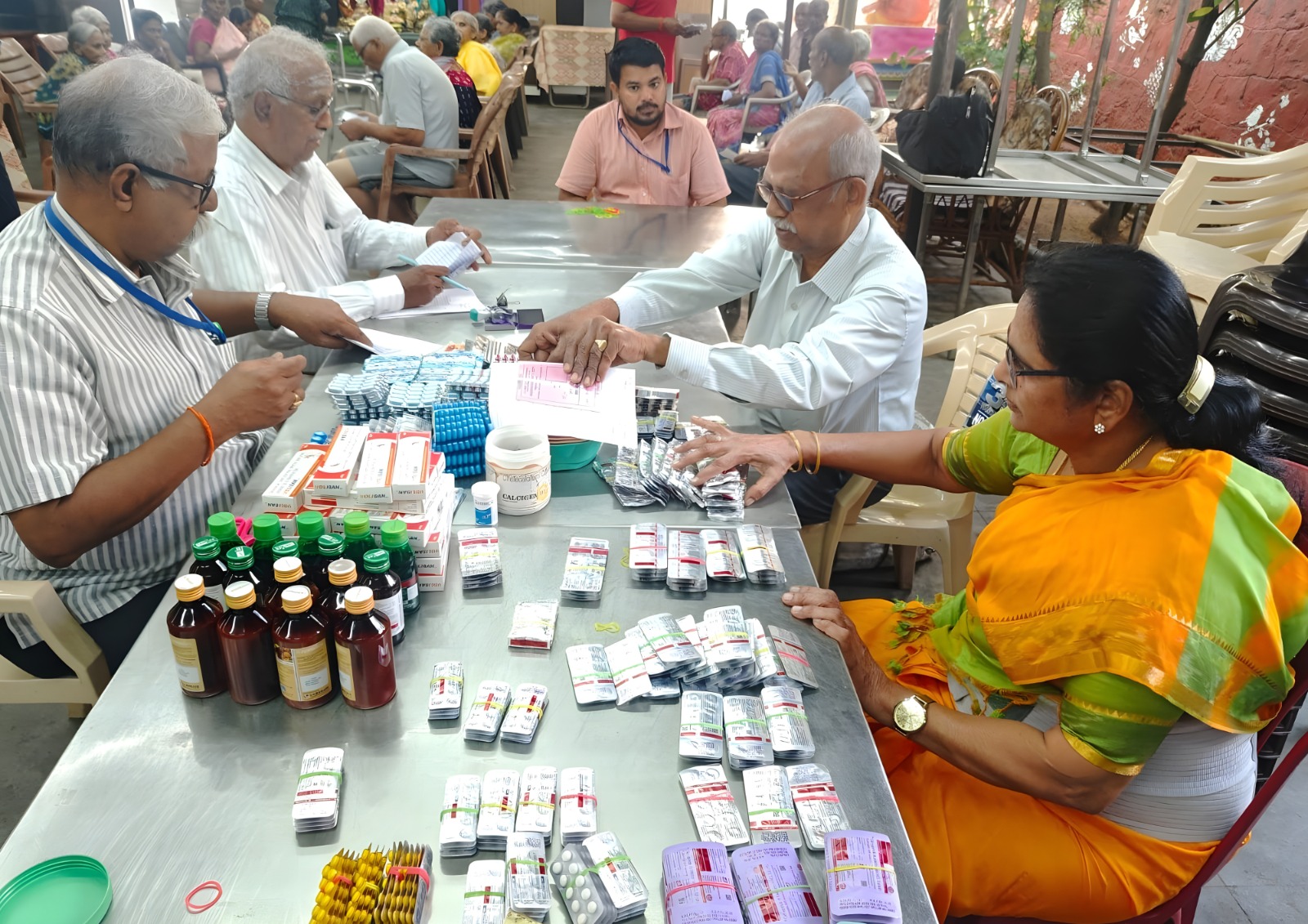 A health worker talking to a group of seniors outdoors.