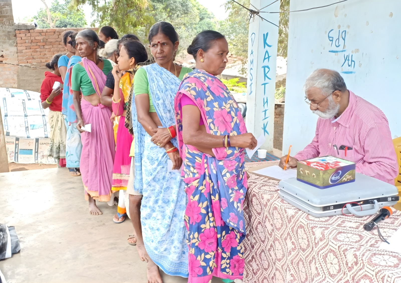 A health worker talking to a group of seniors outdoors.